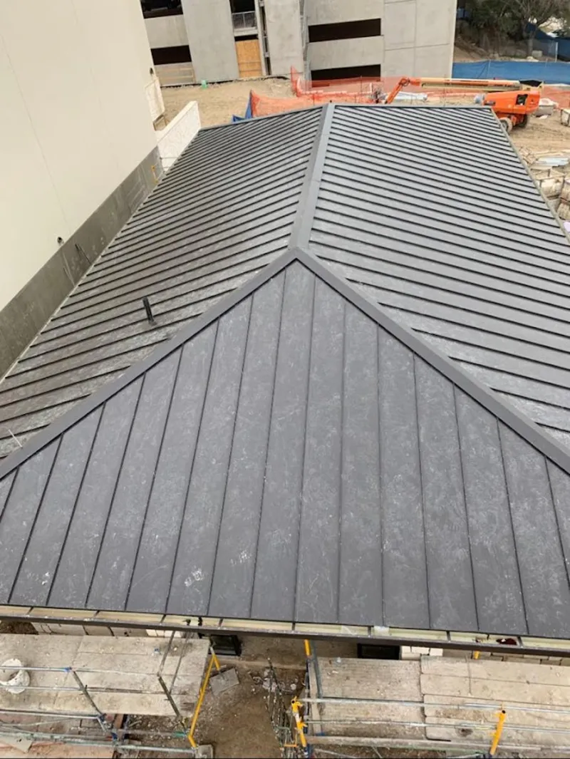 Commercial metal roof construction with crane equipment in Holliston